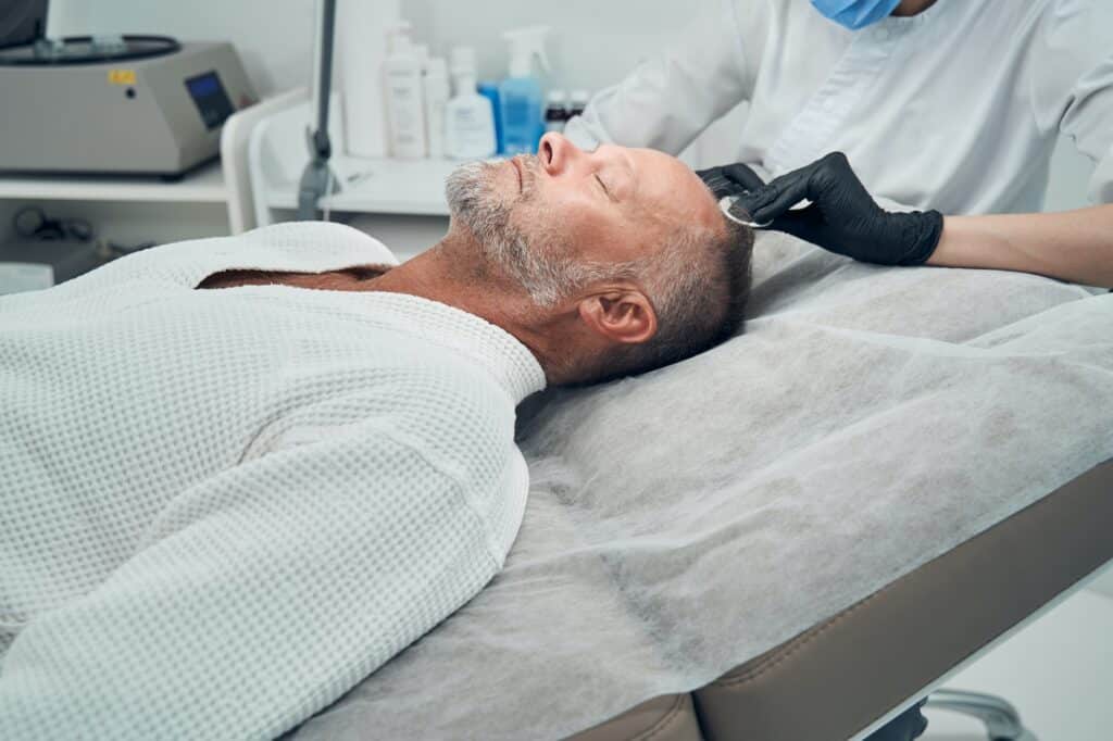 Man receiving hair loss treatment in cosmetology clinic